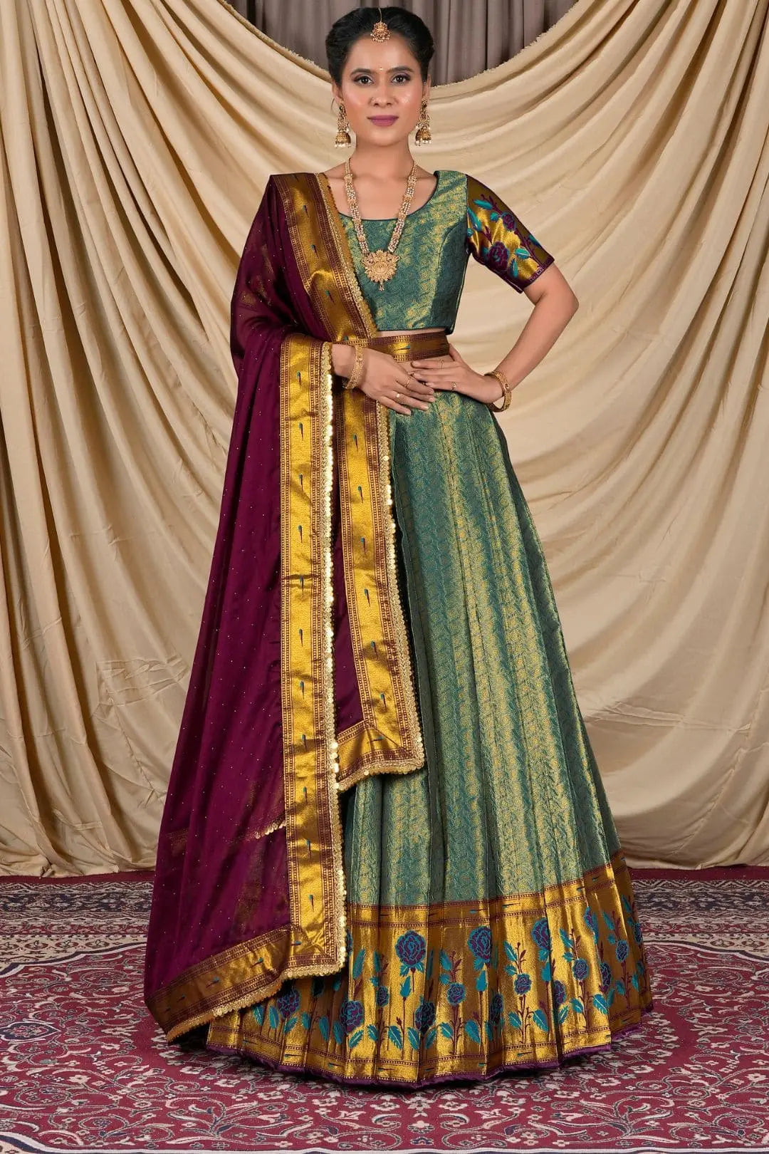 Woman wearing a traditional green and gold dress with a purple dupatta