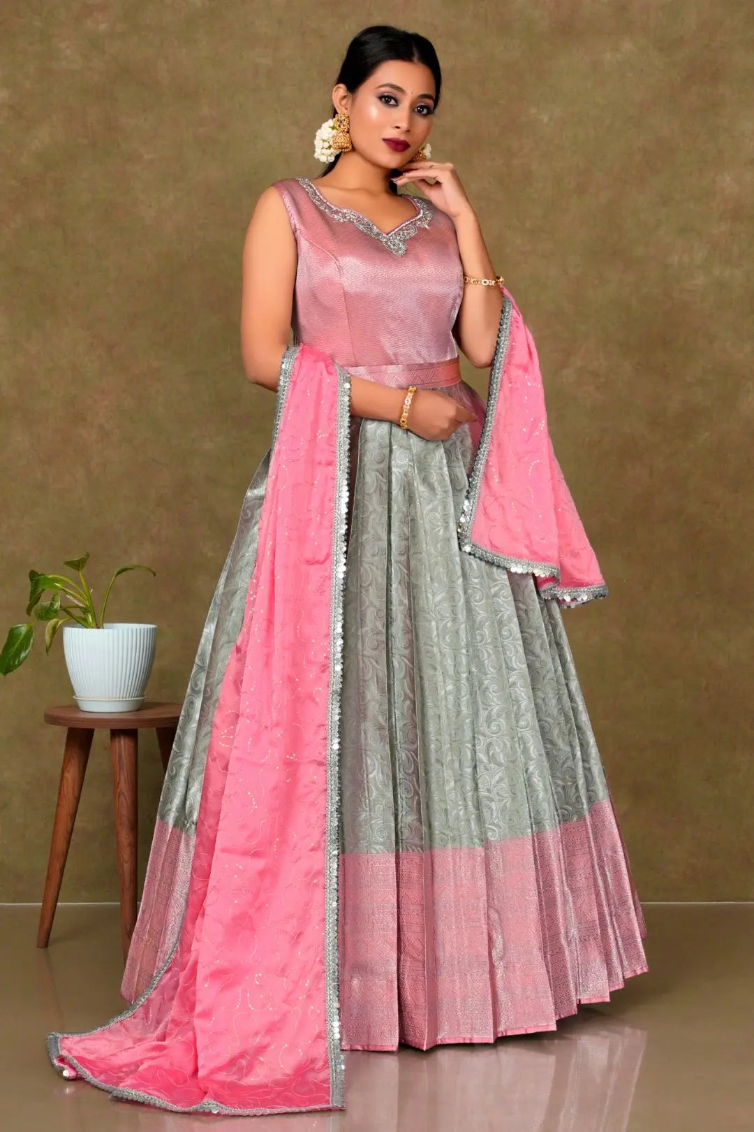Woman wearing a pink and gray traditional outfit with a matching dupatta