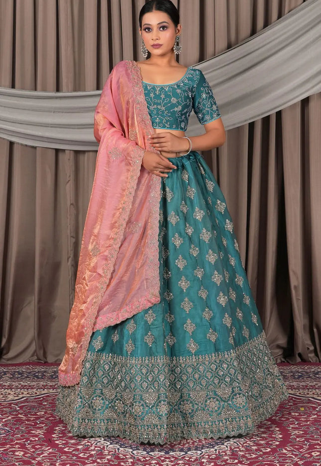 Woman wearing a traditional teal and pink outfit with a matching dupatta