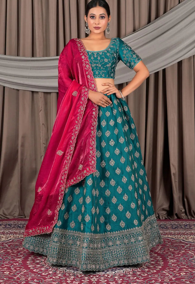 Woman wearing a traditional teal and pink lehenga with a draped dupatta