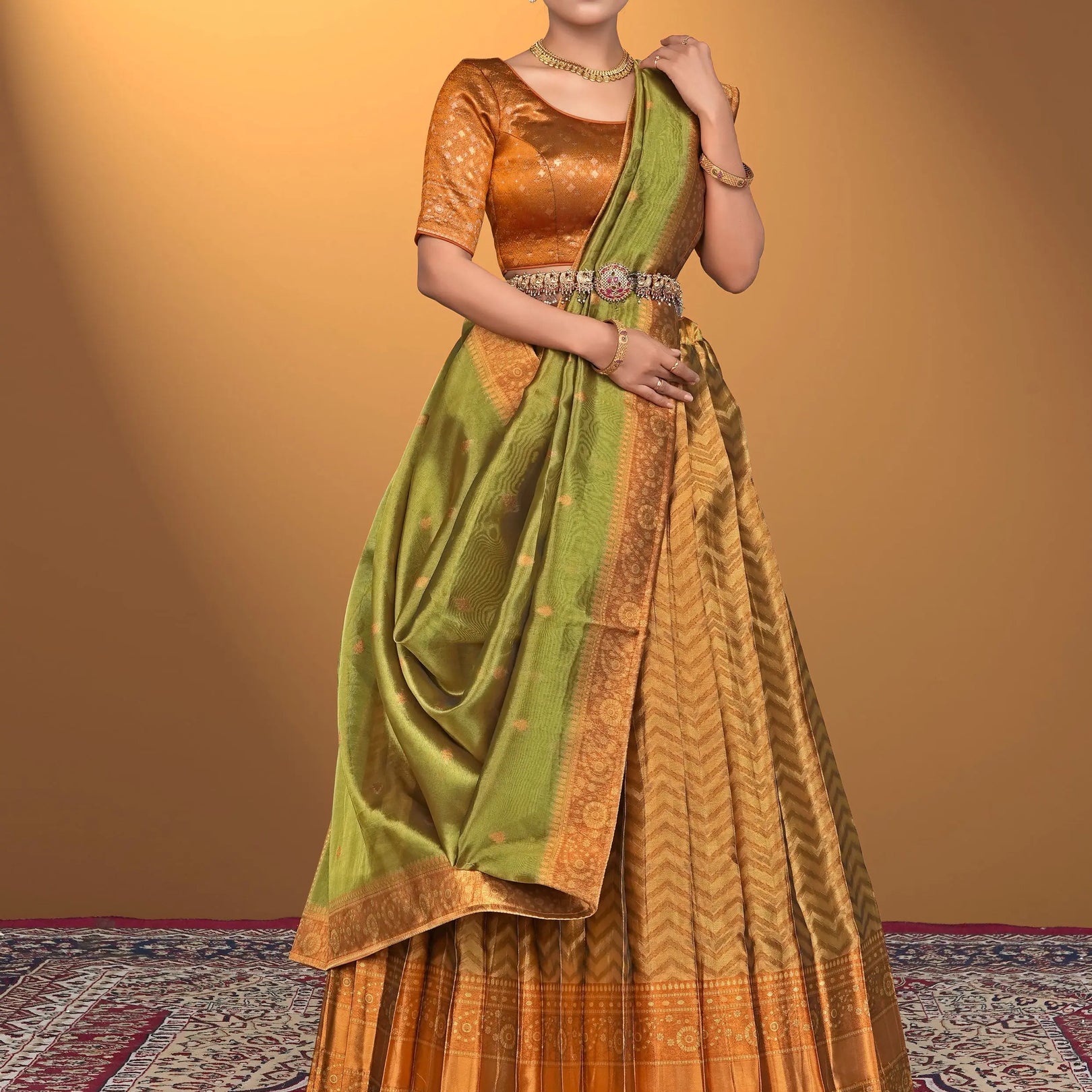 Woman wearing a traditional outfit with a green and orange lehenga choli