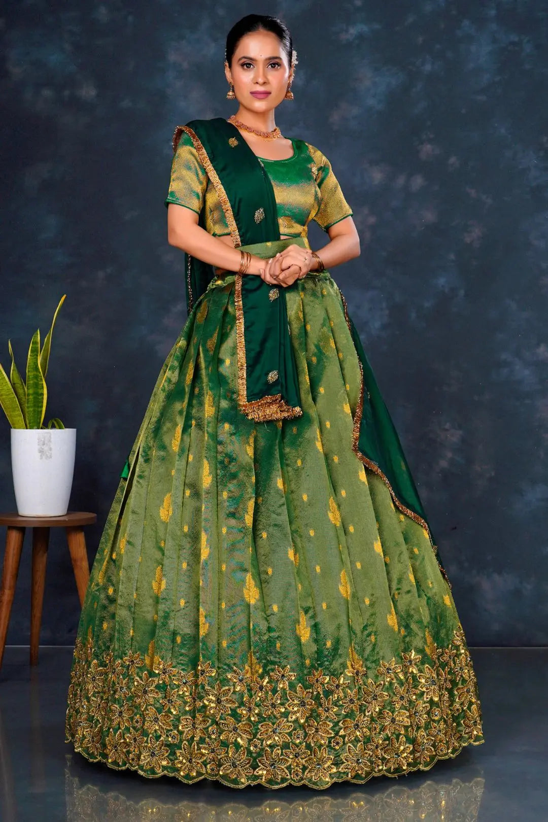 Woman wearing a green traditional outfit with gold embroidery