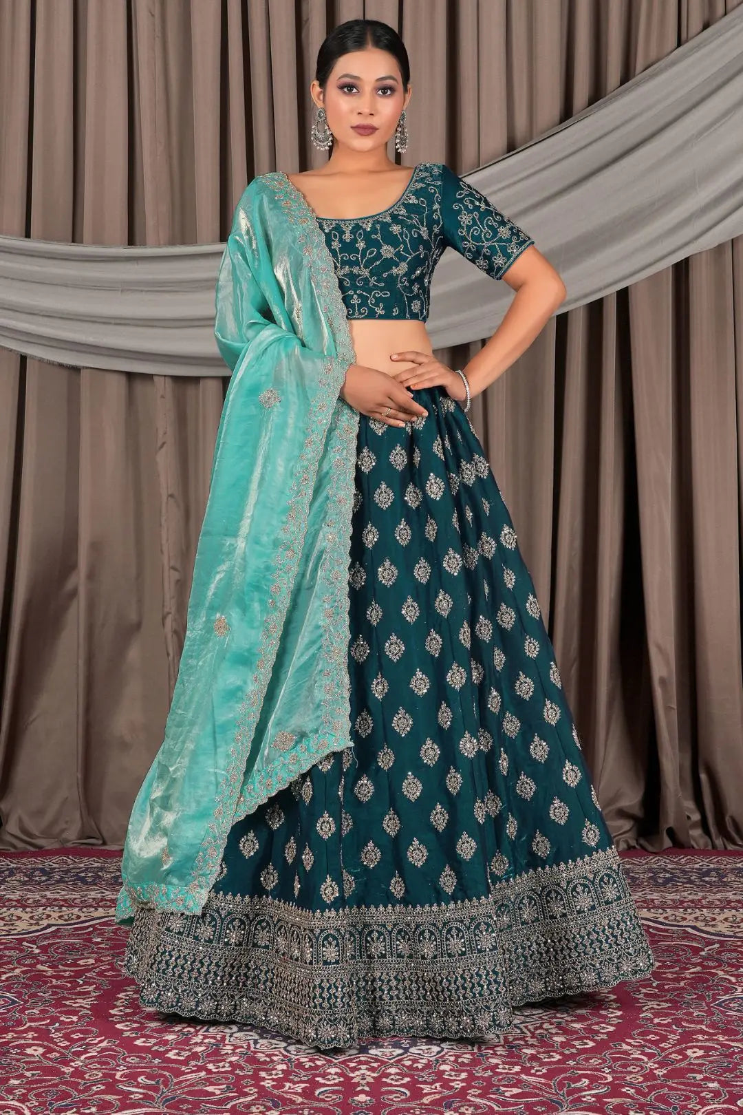 Woman wearing a traditional teal and silver embroidered outfit with a matching dupatta