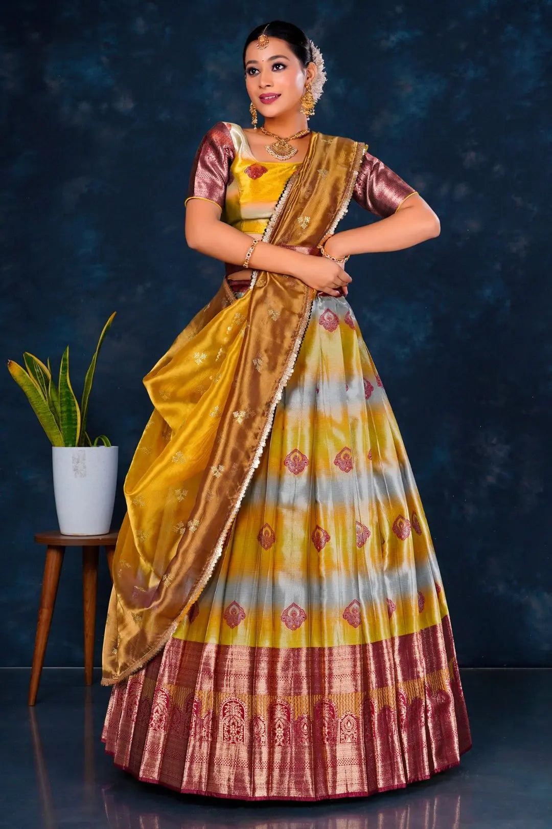 Woman in a traditional musterd and maroon half saree with dupatta