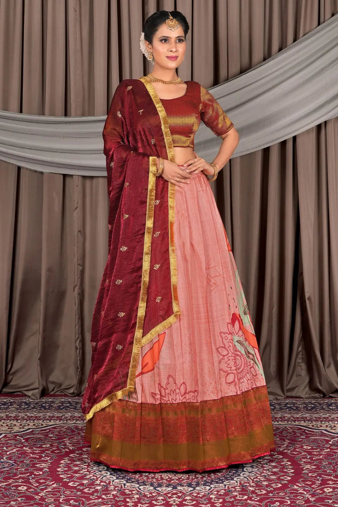 Woman wearing a traditional maroon and pink saree with a gold border