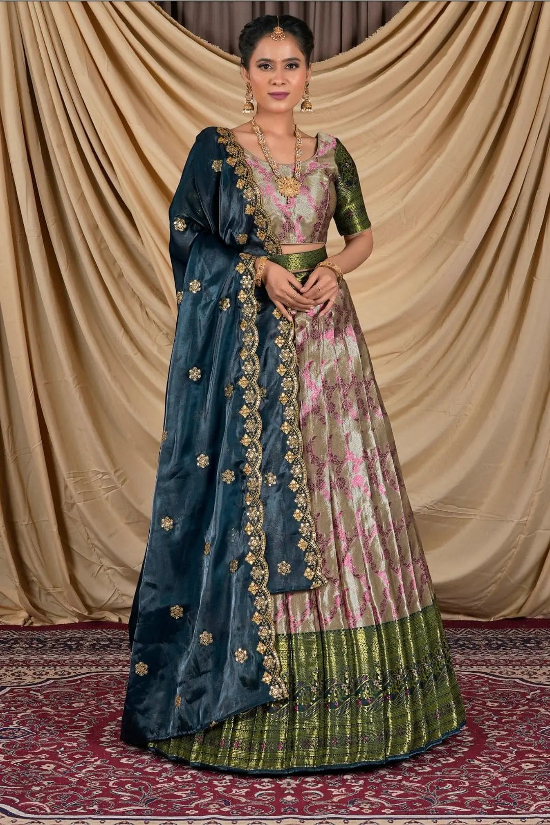 Woman wearing a traditional blue and pink lehenga choli with a gold border.