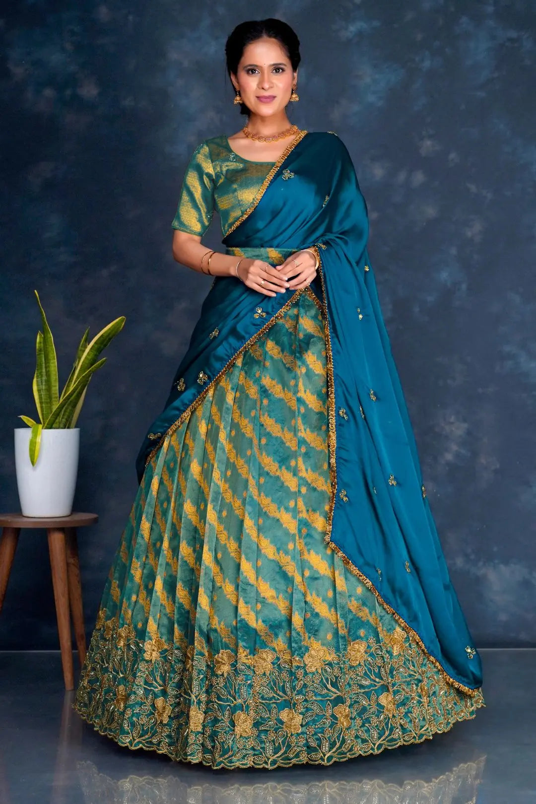 Woman wearing a traditional teal and gold lehenga choli with dupatta
