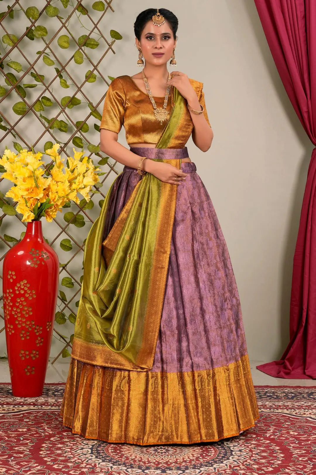 Woman wearing a traditional outfit with a green and purple lehenga choli with dupatta