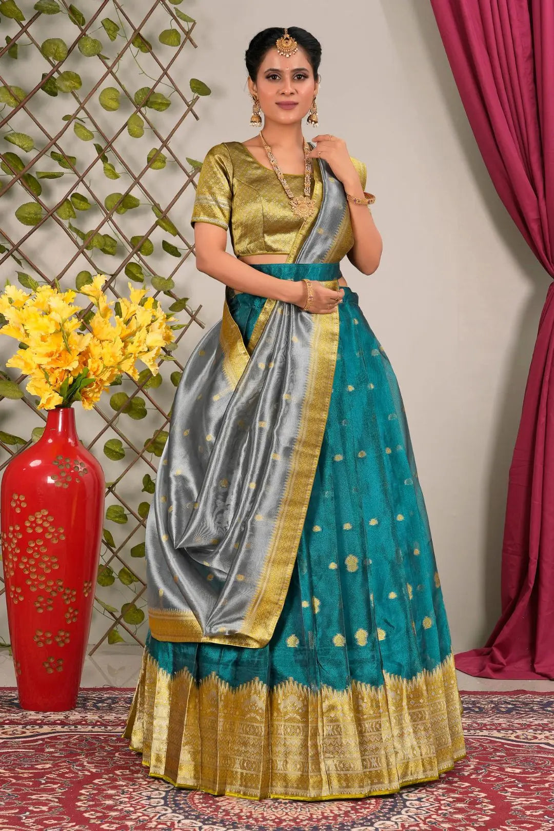 Woman in a traditional outfit with a teal and gold lehenga choli with dupatta