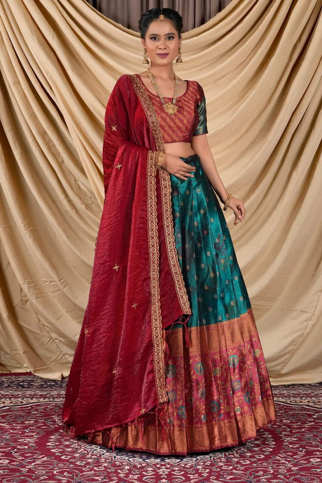 Woman wearing a traditional red and rama lehenga with a gold border