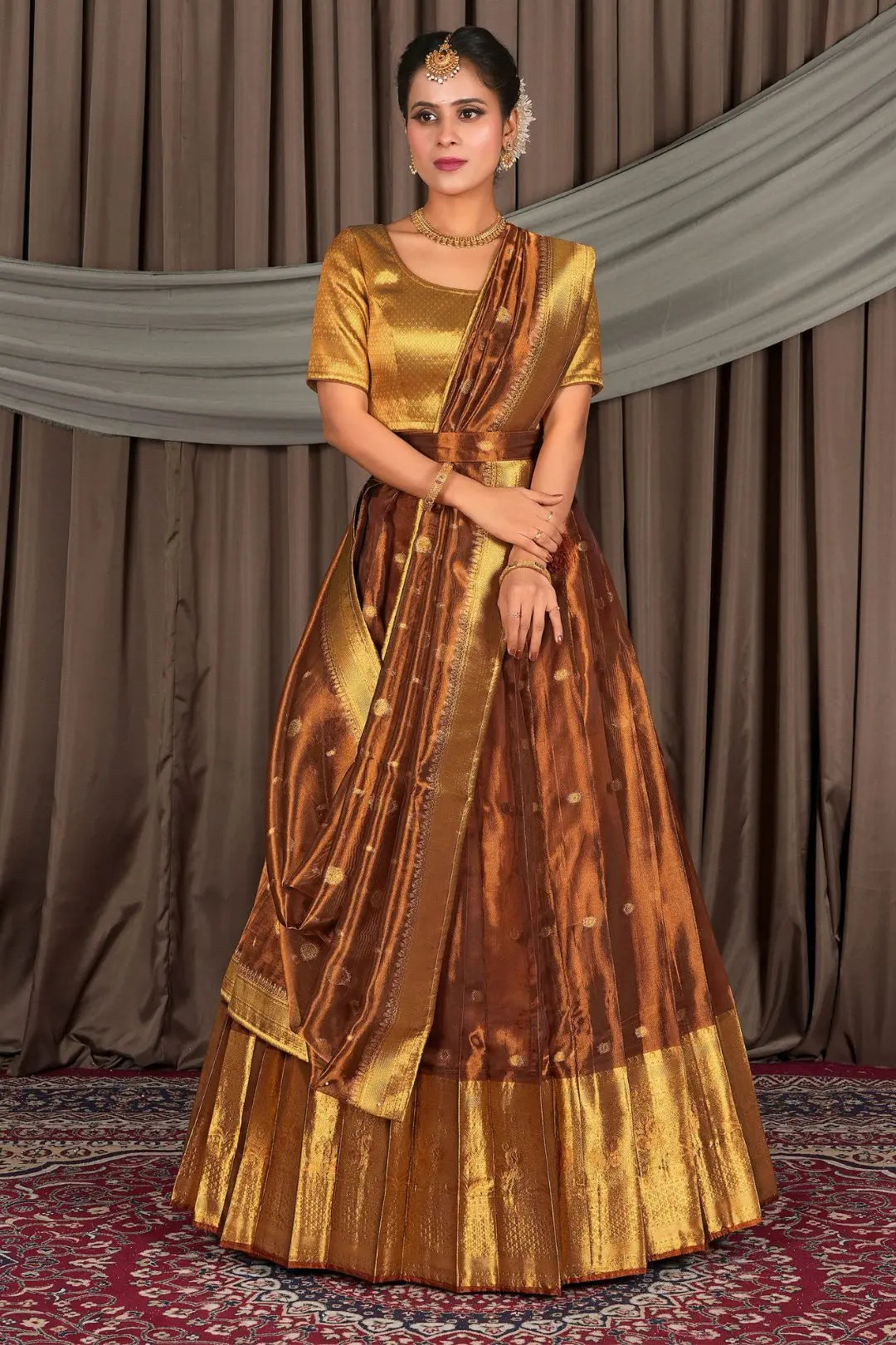 Woman wearing a traditional gold and rust lehenga choli with dupatta