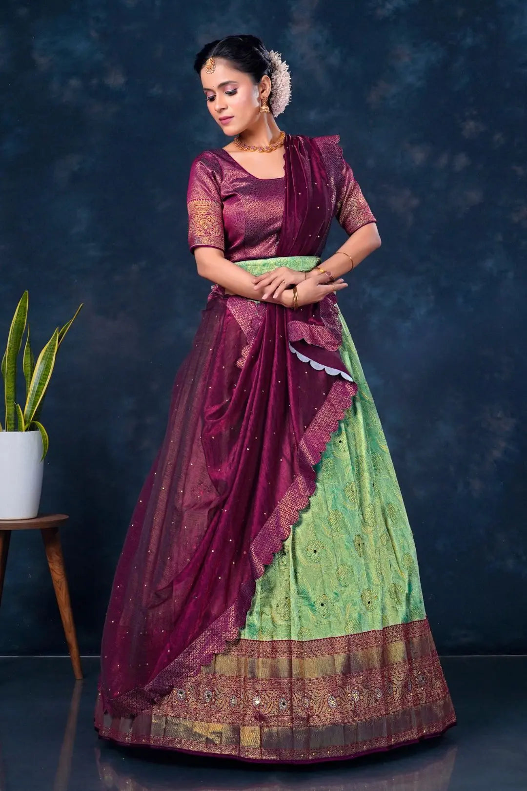 Woman wearing a traditional maroon and green lehenga choli with dupatta
