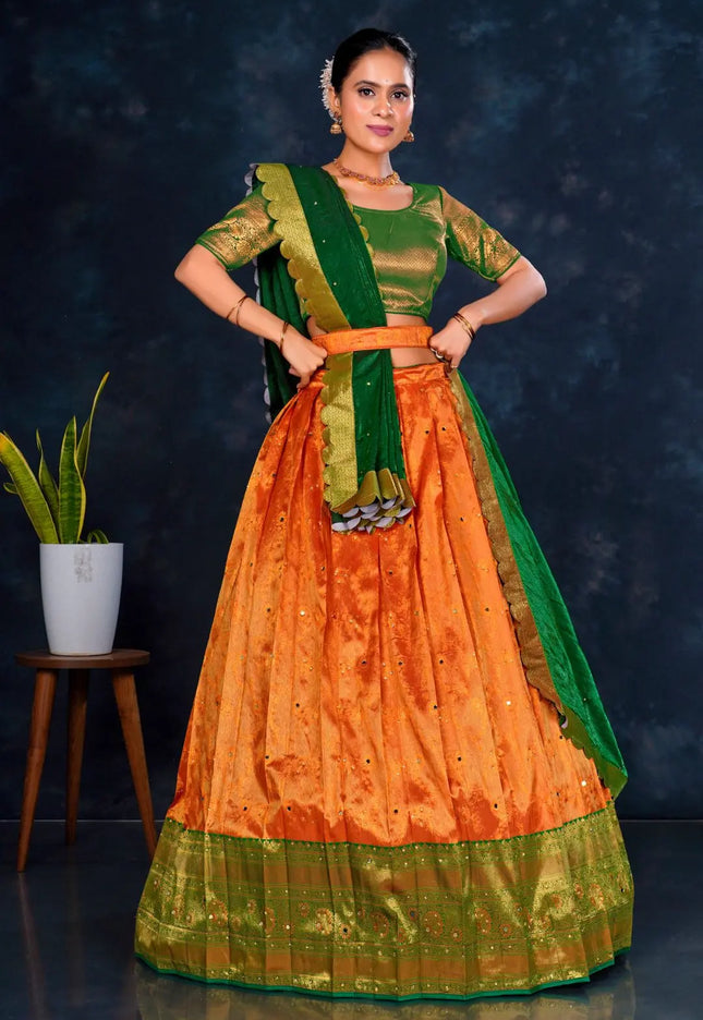 Woman wearing an orange and green traditional lehenga choli with dupatta