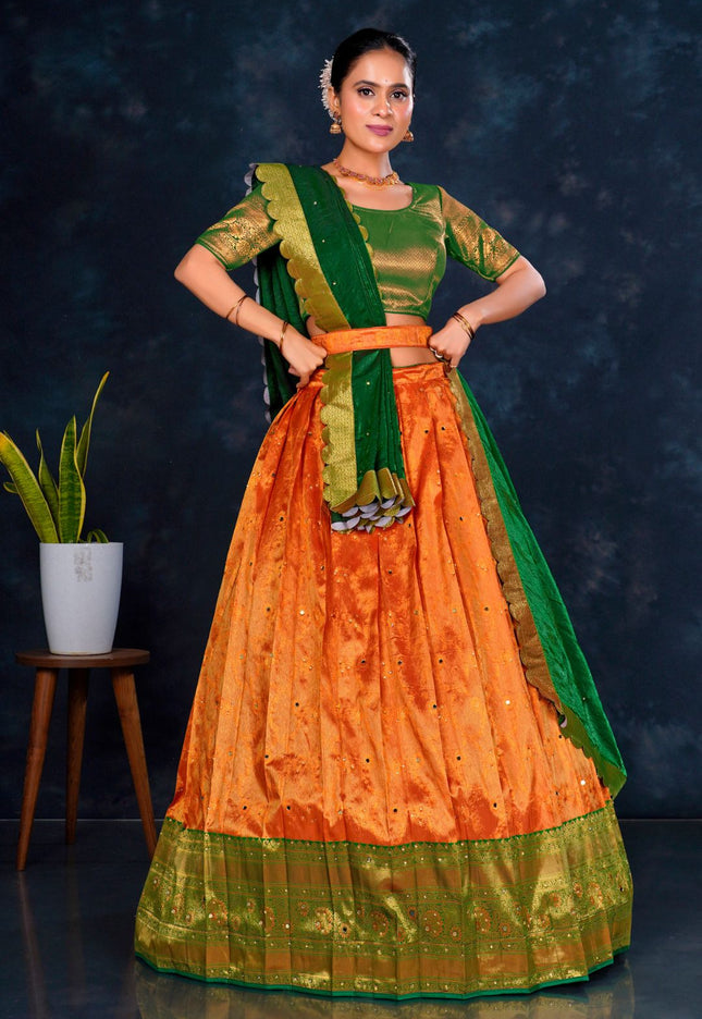 Woman wearing an orange and green traditional lehenga choli with dupatta
