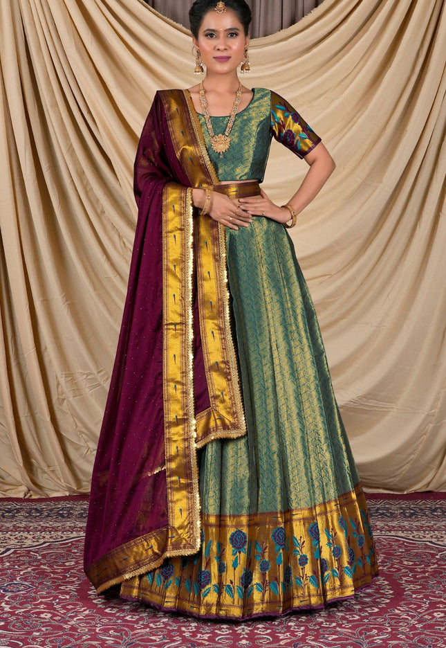 Woman wearing a traditional green and gold dress with a purple dupatta
