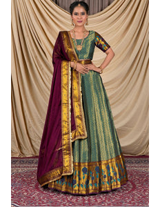 Woman wearing a traditional green and gold dress with a purple dupatta