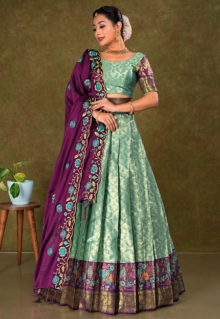 Woman wearing a green and purple traditional outfit with a matching lehenga and choli
