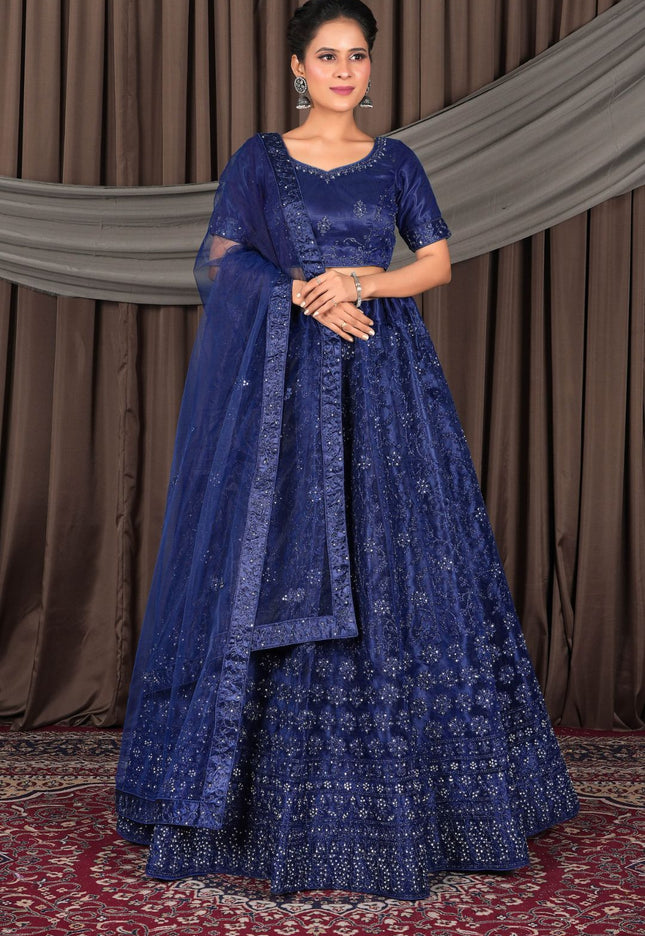 Woman wearing a traditional blue embroidered outfit with a dupatta