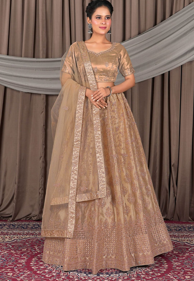 Woman wearing a traditional beige embroidered outfit with a dupatta