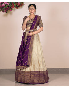 Woman wearing a traditional outfit with a purple and beige lehenga choli