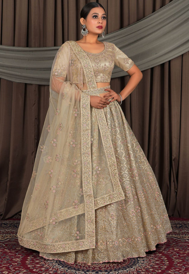 Woman wearing a traditional beige embroidered outfit with a matching dupatta