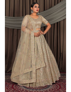 Woman wearing a traditional beige embroidered outfit with a matching dupatta