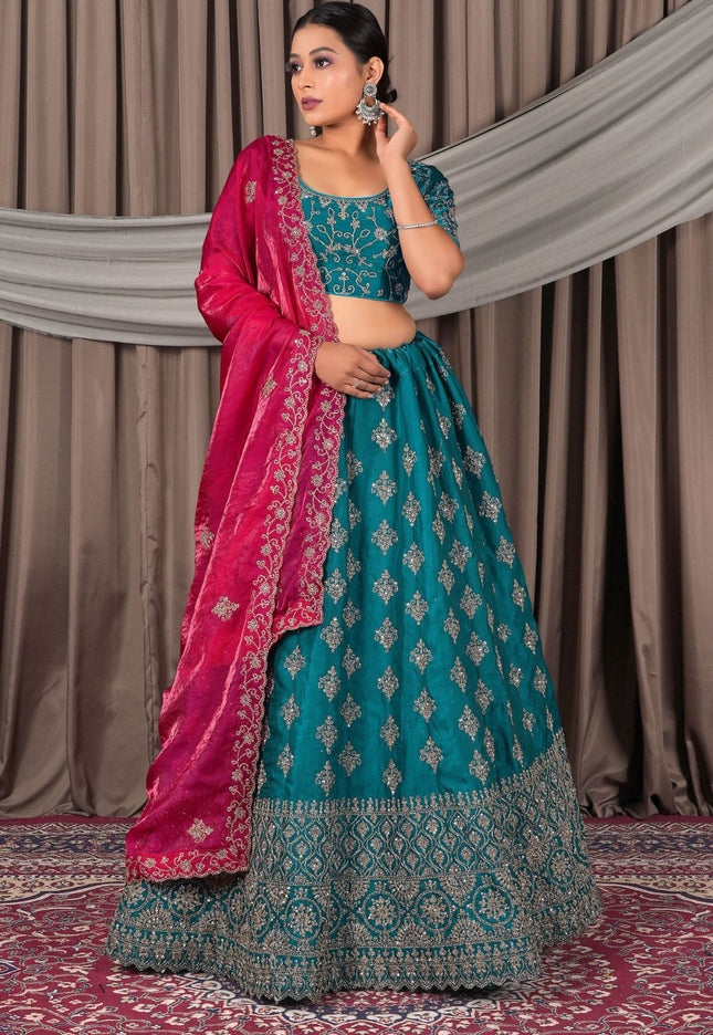 Woman wearing a traditional teal and pink saree with a matching blouse
