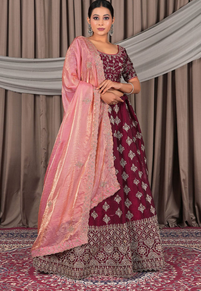 Woman wearing a maroon and pink traditional outfit with a matching dupatta