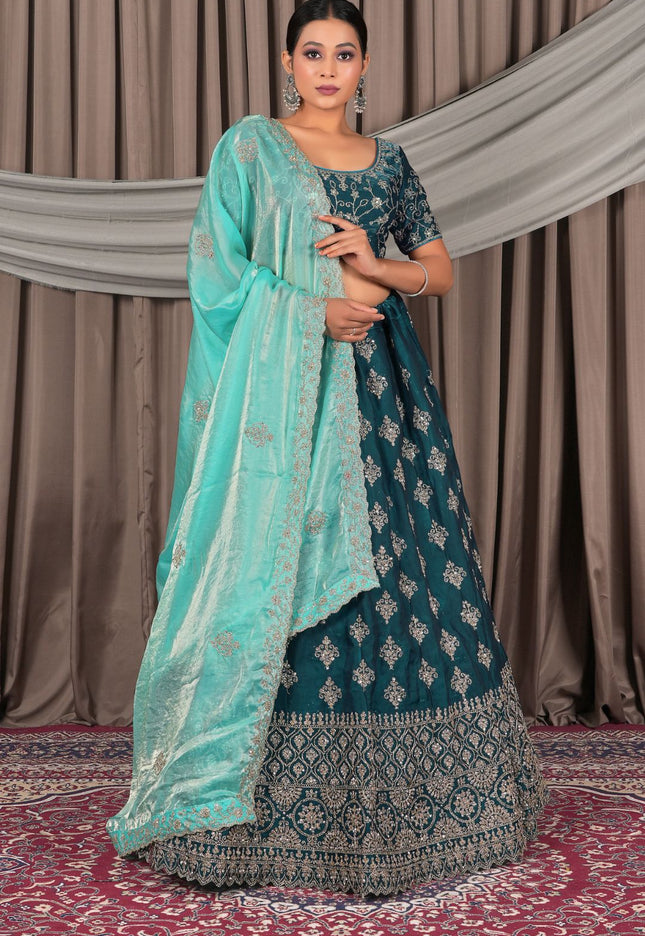 Woman wearing a teal and light blue traditional outfit with a matching dupatta