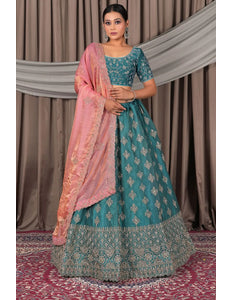Woman wearing a traditional teal and pink outfit with a matching dupatta