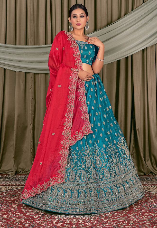 Woman wearing a traditional blue and pink embroidered lehenga with a red dupatta