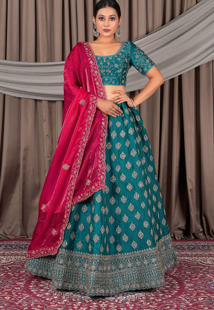 Woman wearing a traditional teal and pink lehenga with a draped dupatta