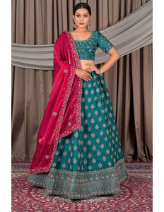 Woman wearing a traditional teal and pink lehenga with a draped dupatta