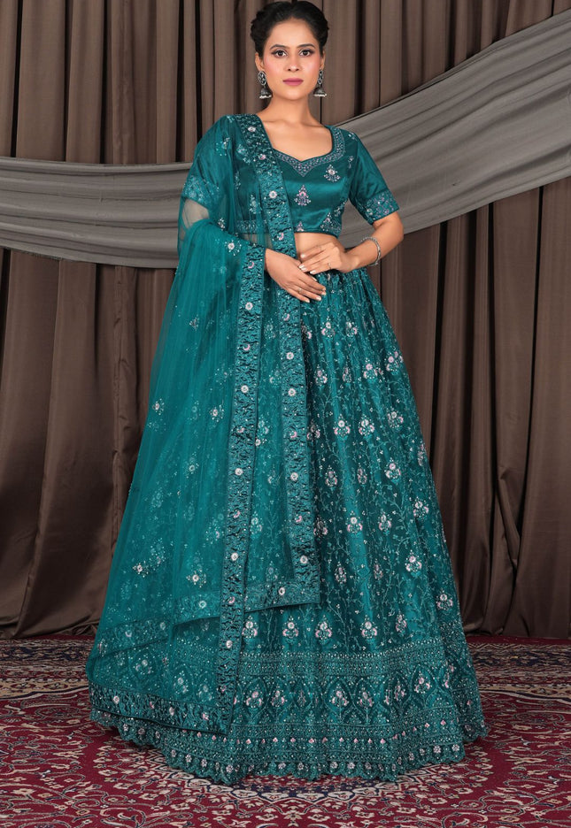 Woman wearing a teal embroidered traditional outfit with a matching dupatta