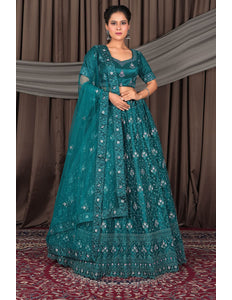 Woman wearing a teal embroidered traditional outfit with a matching dupatta