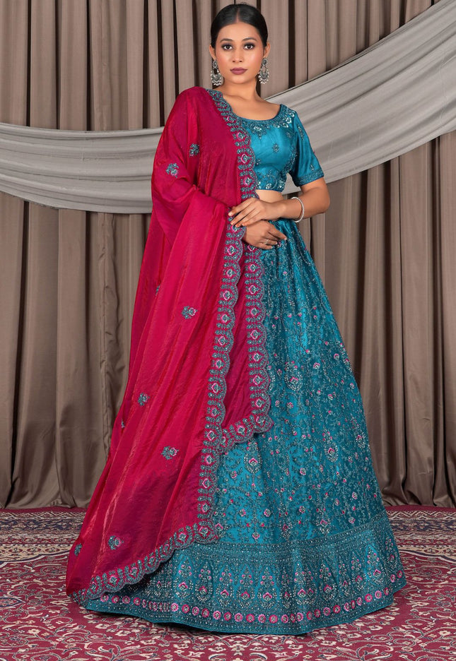 Woman in a blue and pink traditional outfit with a draped pink dupatta