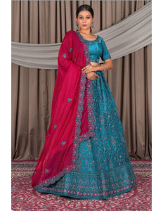 Woman in a blue and pink traditional outfit with a draped pink dupatta