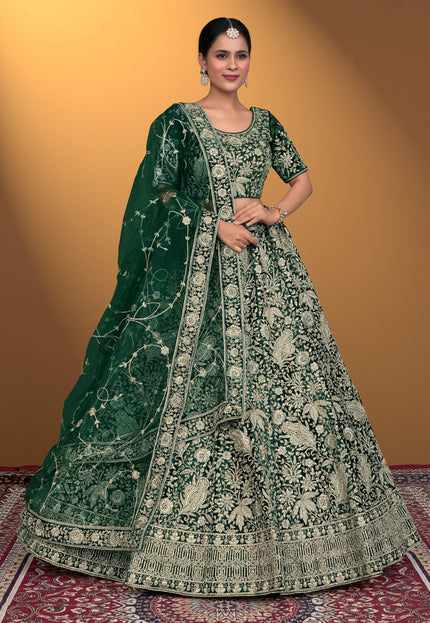 Woman wearing a green embroidered traditional outfit on a patterned rug with a yellow background