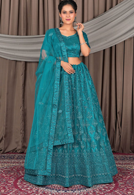 Woman wearing a teal embroidered traditional outfit with a matching dupatta
