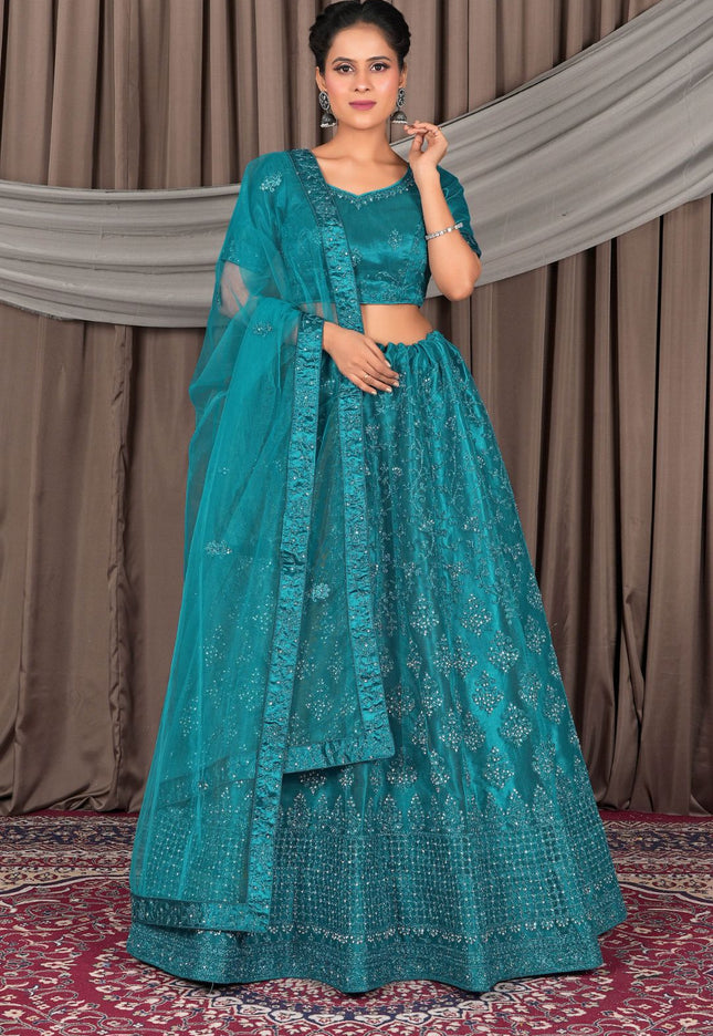 Woman wearing a teal embroidered traditional outfit with a matching dupatta