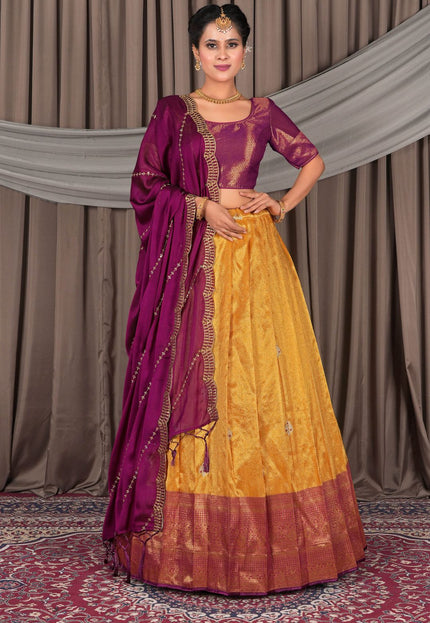 Woman wearing a traditional yellow and purple saree with a matching blouse