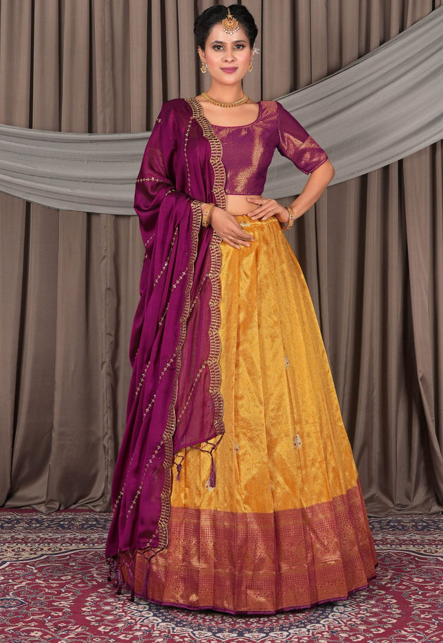 Woman wearing a traditional yellow and purple saree with a matching blouse