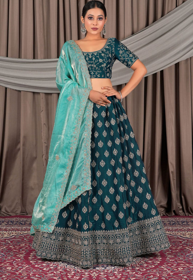 Woman wearing a traditional teal and silver embroidered outfit with a matching dupatta