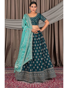 Woman wearing a traditional teal and silver embroidered outfit with a matching dupatta