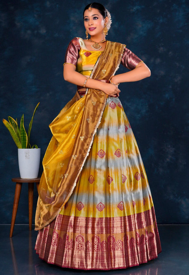Woman in a traditional musterd and maroon half saree with dupatta