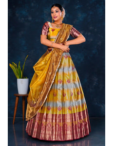 Woman in a traditional musterd and maroon half saree with dupatta