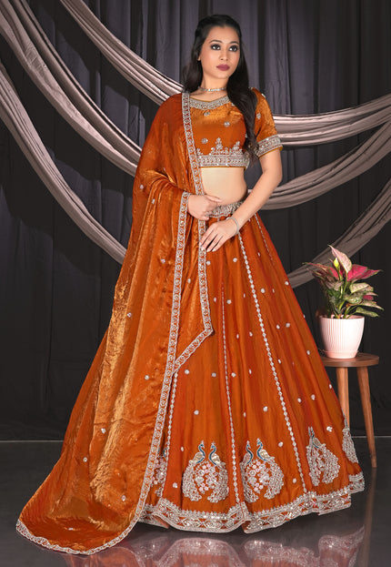 Woman in an orange embroidered traditional lehenga choli with matching dupatta