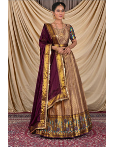 Woman wearing a traditional gold and purple lehenga choli with dupatta
