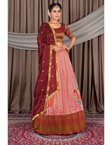 Woman wearing a traditional maroon and pink saree with a gold border