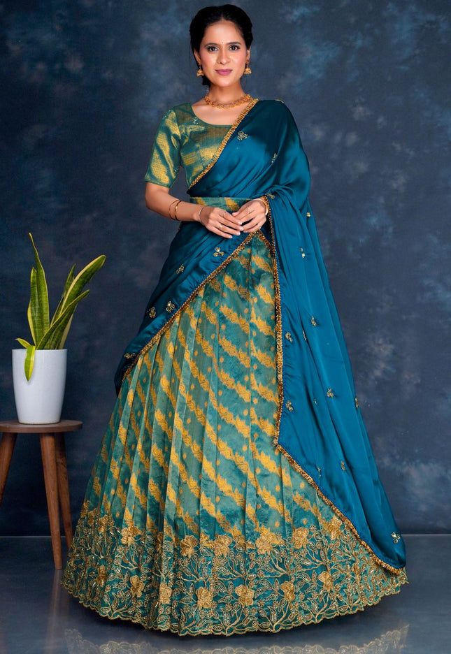Woman wearing a traditional teal and gold lehenga choli with dupatta